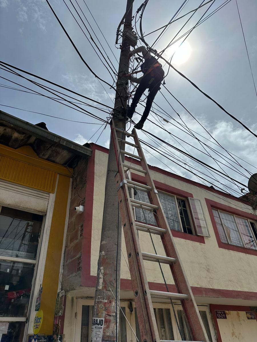 Técnico en escalera haciendo tendido de red en poste de servicios